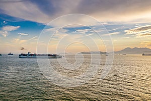 Container ships pass in and out Victoria Harbour at dusk