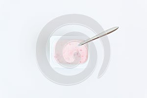 Container with strawberry yogurt and spoon, top view, isolated o