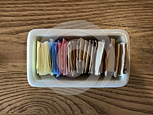Container of sugar nd sugar substitute packets on a restaurant table