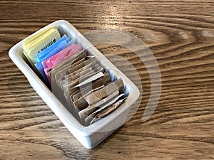 Container of sugar nd sugar substitute packets on a restaurant table