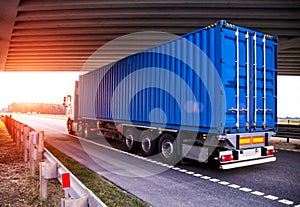 A container truck with a semi-trailer transports cargo from a port to another country along a highway in the summer