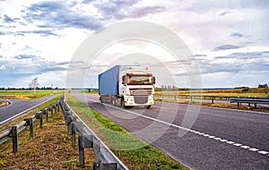 A container truck with a semi-trailer transports cargo from a port to another country along the highway in the summer