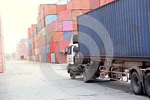 A container truck sits behind a pile of containers