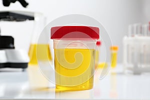 Container with urine sample for analysis on table photo