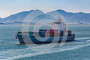 Container vessel passes underway along Gwangyang bay shore photo