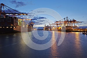 Container vessel at terminal in harbor in the evening