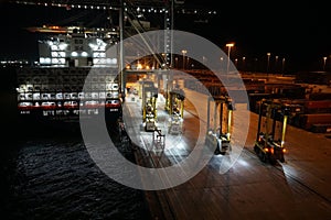 Container vessels under cargo operation by gantry cranes during night in port of Kingston.