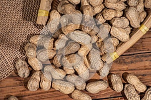 The container on the wood grain table is full of peanuts