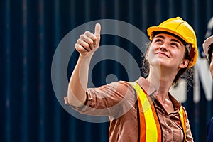 Container yard workers woman in yellow helmet smiling and thumb up with her collegue on second floor photo