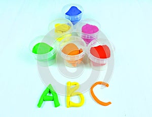 Containers with colorful plasticine and the child made numbers one , two, three.  white  wooden background