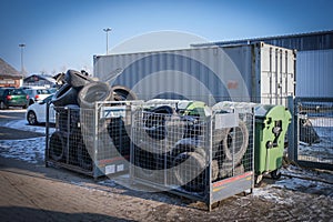 containers filled with old tires and car parts in the yard of a car repair shop