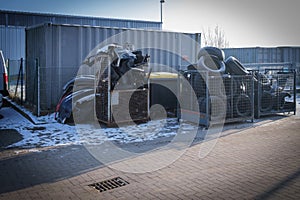 containers filled with old tires and car parts in the yard of a car repair shop