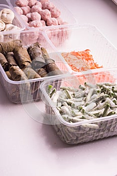 Containers with frozen vegetables and semi-finished meat products from the refrigerator. meatballs, dumplings, dolma in grape
