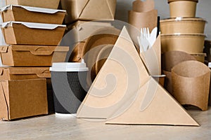 Containers for pizza and sandwich made of triangular paper on the background of disposable tableware.