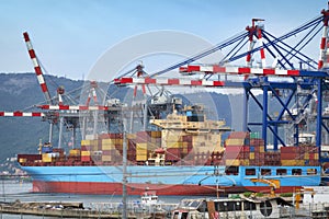 Containers ship discharging and loading container cargo at harbor terminal