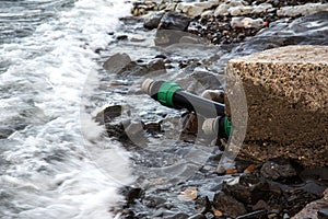 Contaminated water, sewage waste is drained through pipe into sea on an unequipped beach. Pollution of environment, ecological cat