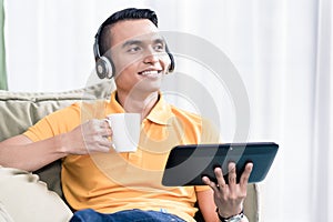 Contemplated man holding coffee cup and digital tablet