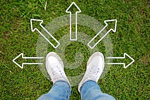 Contemplating Choices. A Man Stands on the Grass, Pondering the Path Ahead Indicated by an Arrow photo