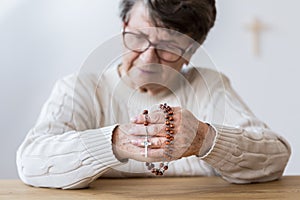 Contemplating elderly woman with rosary