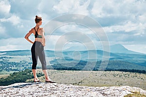 Contemplation. Pilates. Sport. Yoga time. Woman in sportswear standing on mountain. Stunning view from hill. Copy space