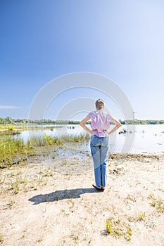 Contemplation by the Water: Woman Overlooking a Serene Lake Landscape