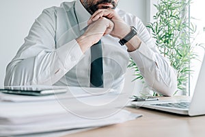 Contemplative businessman propping chin with hands in office