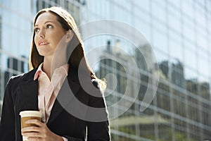 Contemplative Businesswoman With Drink Outside Building