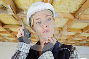contemplative female builder using walkie talkie