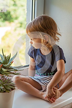 Contemplative girl sitting on a sill