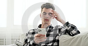 Contemplative Man with Phone on Sofa