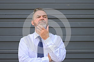 Contemplative senior businessman stroking his beard outdoors