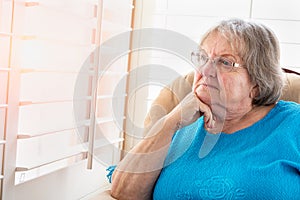 Contemplative Senior Woman Gazing Out of Her Window photo