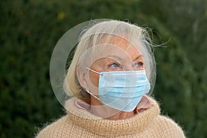 Contemplative senior woman wearing a face mask