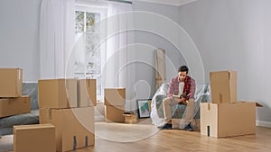 Contemplative Smart Young Man Reads His Favourite Books While in the Process of Moving Into His New