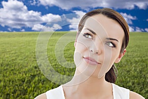 Contemplative Woman in Grass Field Looking Up and Over