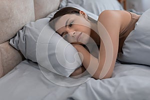 Contemplative woman resting in bed with pensive look