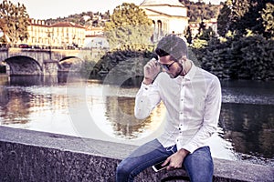 Contemplative young man sitting beside river