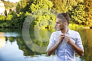 Contemplative young man sitting beside river