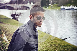 Contemplative young man sitting beside river