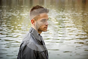 Contemplative young man standing beside river