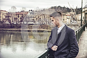 Contemplative young man standing beside river