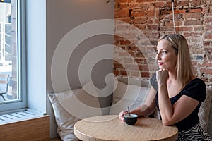 Contemplative Young Woman Enjoying Coffee in a Chic Cafe