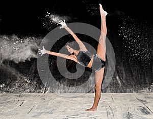 Contemporary ballet dancer dancing on the stage with flour