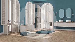 Contemporary bathroom in blue tones in vintage apartment with arched window. Freestanding bathtub, washbasins and mirrors, carpet
