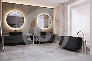 Contemporary bathroom interior with bath tub, illuminated round mirrors and black washbasins.