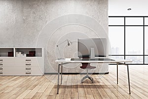 Contemporary concrete office interior with desktop and computer, other pieces of furniture and objects, window with city view and
