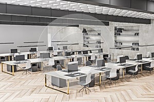 Contemporary concrete and wooden coworking office interior with multiple workplaces and bookcase shelves with books and folders.