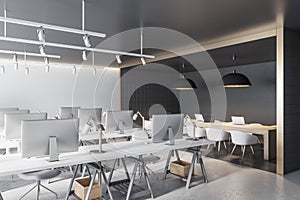 Contemporary coworking office interior with black tile partition, equipment, furniture and daylight.