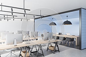 Contemporary coworking office interior with blue tile partition, equipment, furniture and daylight.