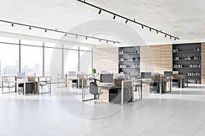 Contemporary coworking office interior with concrete floor, windows with panoramic city view and workplace furniture. Corporate
